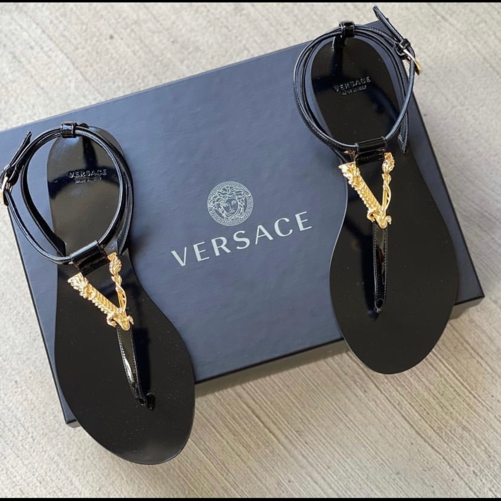 Black Versace sandals with gold Versace monogram.